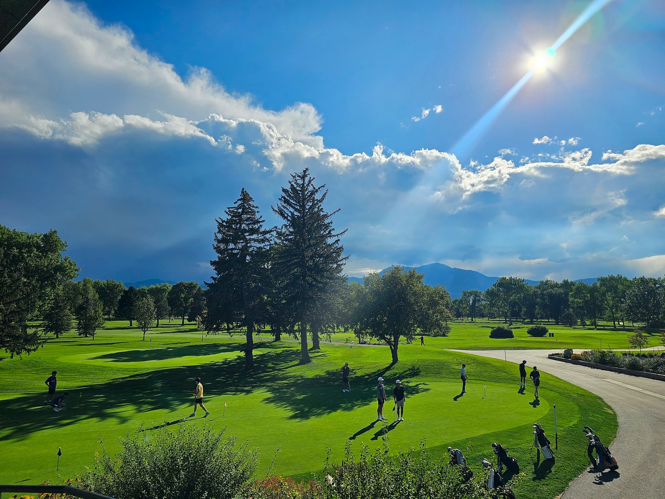 Group of golfers putting on the green with dramatic mountain backdrop