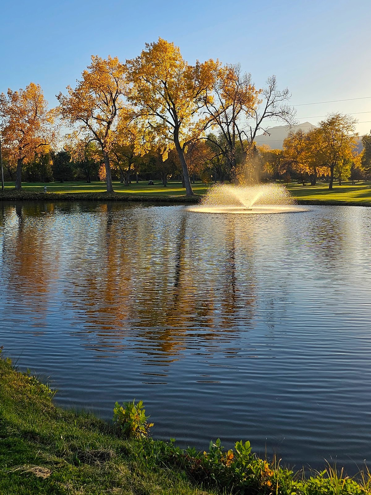 Golden hour reflection on the water feature with autumn trees and mountain silhouette